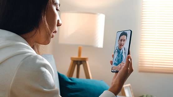 Woman video chatting from her living room with her doctor on her smartphone 