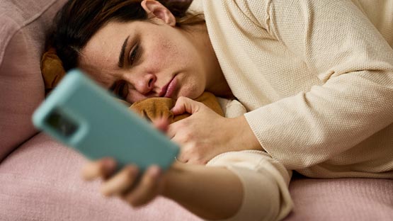 Woman laying on couch checking smartphone