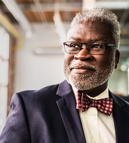 A senior male with glasses smiling and looking out the window