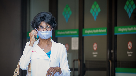 woman adjusting her mask outside AHN Hospital entrance